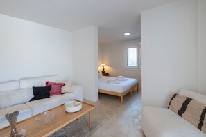 A modern, minimalist bedroom with a single bed, a white sofa, and a small table. - Astrid – A Serene Rooftop Escape in Athens (Athens)