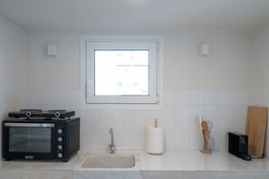 A kitchen with a built-in oven, a sink, a window, and a wooden cutting board. - Astrid – A Serene Rooftop Escape in Athens (Athens)