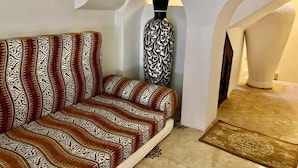 Um quarto com um sofá estampado, um vaso decorativo e um tapete.