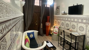 Uma sala de estar com sofá, mesa de jantar e cadeiras, televisão e objetos decorativos.