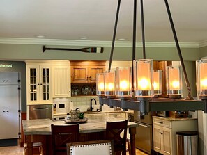 Cocina con armarios de madera, una isla central e iluminación colgante.