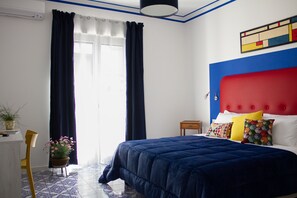 Quarto de hotel com uma cama, uma escrivaninha e uma cadeira.