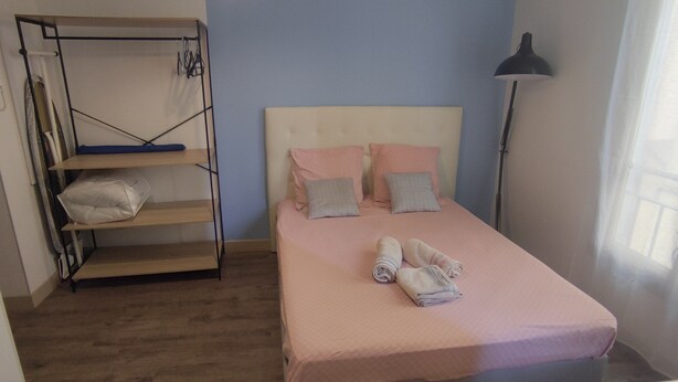 A bedroom with a bed, a shelf unit, and a floor lamp. - Le Port - Cosy studio perfectly located (Nice)