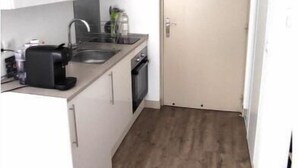 A compact kitchen with white cabinets, a built-in oven, a coffee maker, and a sink. - Le Port - Cosy studio perfectly located (Nice)