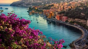 A coastal town with buildings along the waterfront, boats in the water, and a road curving through the town. - Le Port - Cosy studio perfectly located (Nice)