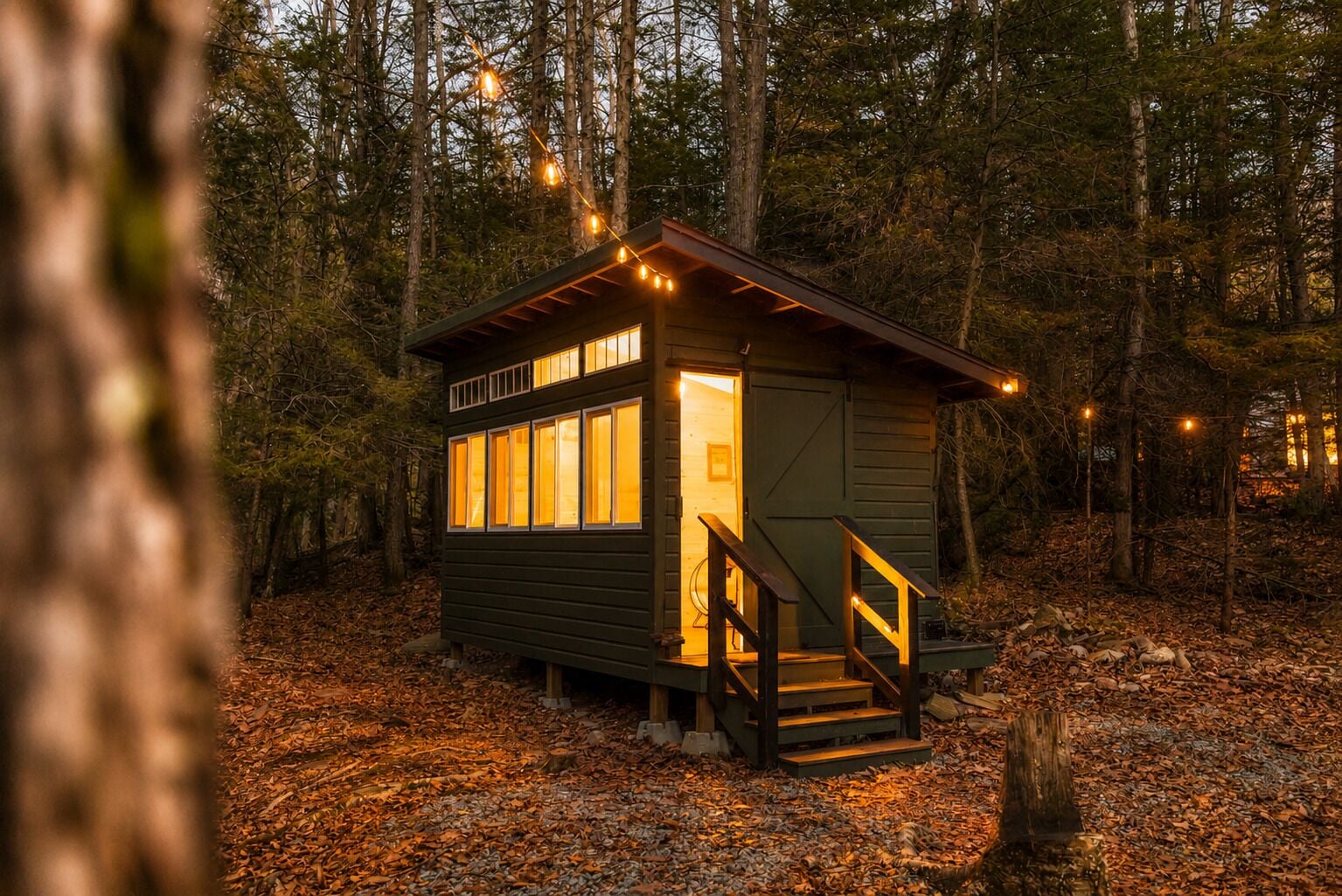 Un piccolo chalet con rivestimento in legno, un portico e una scala che conduce all'ingresso.