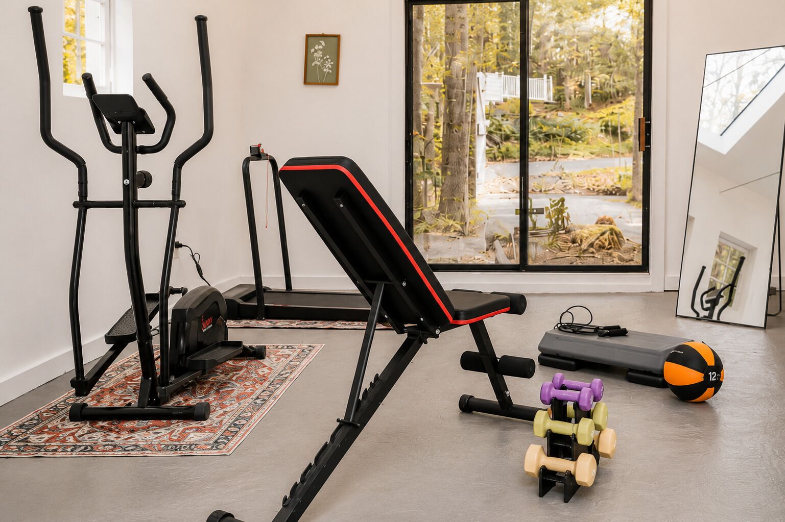 A home gym with exercise equipment including a treadmill, elliptical, and bench.