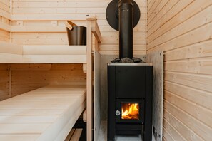 A wooden cabin with a built-in wood stove, a bunk bed, and a small table.