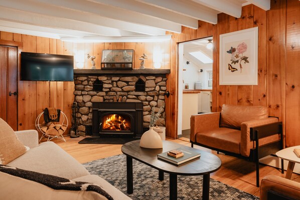 Una sala de estar con chimenea de piedra, muebles de cuero y un televisor de pantalla plana montado en la pared.