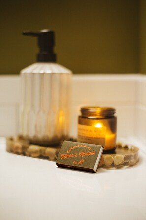 A bathroom with a soap dispenser, a candle, and a small sign on the counter.