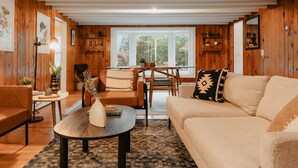 Un salon chaleureux avec des murs en bois, un canapé, une table basse et un coin repas avec une table et des chaises.