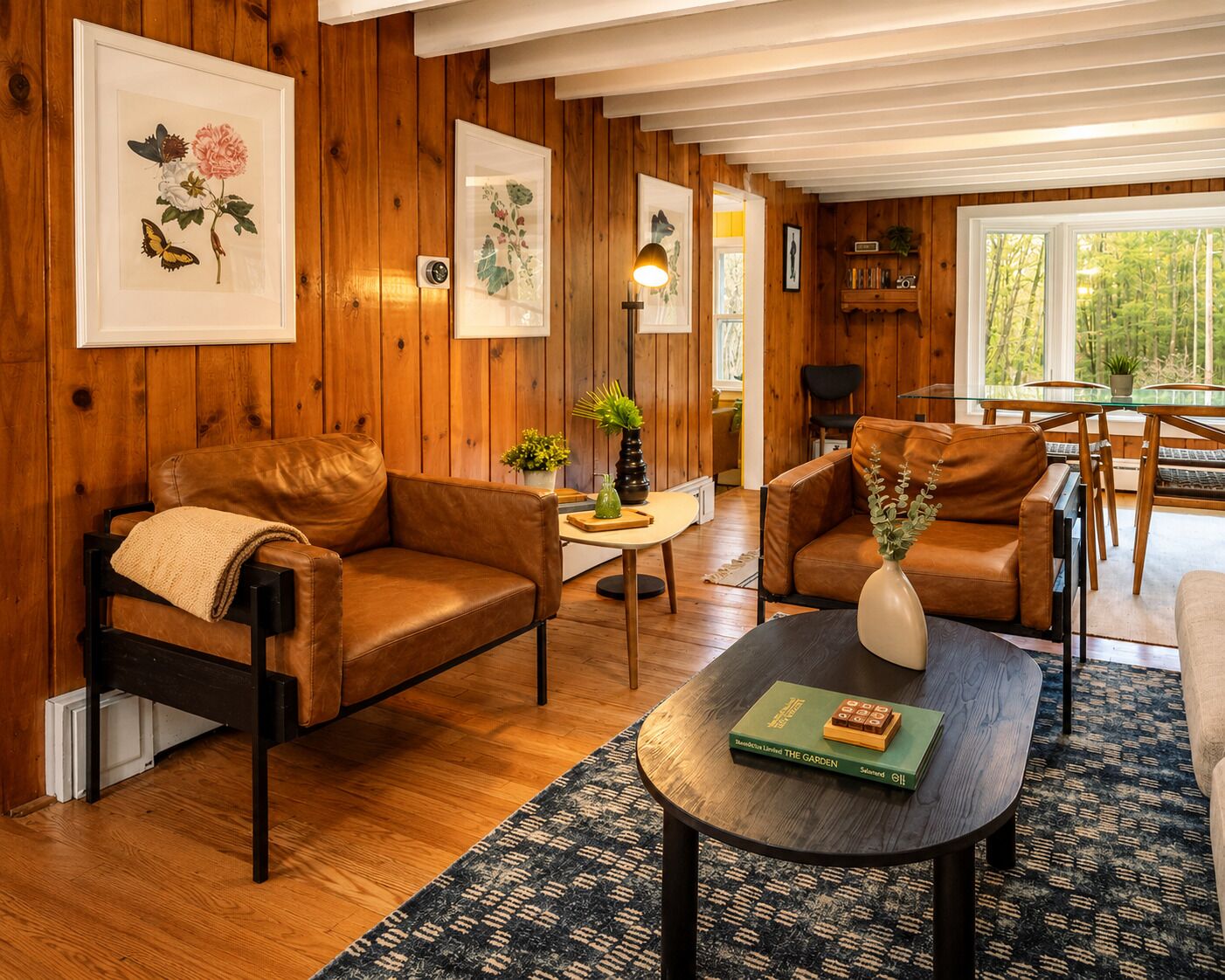 A cozy living room with leather sofas, a coffee table, and framed botanical prints on the walls.