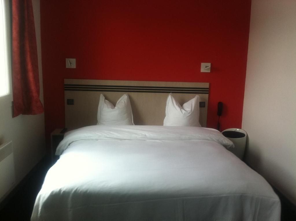 Ein Hotelzimmer mit einem Bett, einem Nachttisch und einer roten Wand.
