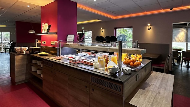 Buffet-alue, jossa on monipuolinen valikoima ruokia, sekä ruokailualue, jossa on pöytiä ja tuoleja.