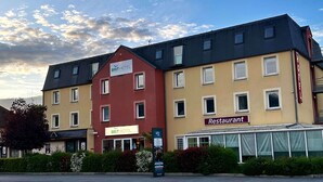 Monikerroksinen rakennus, jossa on kyltit «BRIT HOTEL» ja «Restaurant» sekä katettu ulkotila, jossa on istuimia.