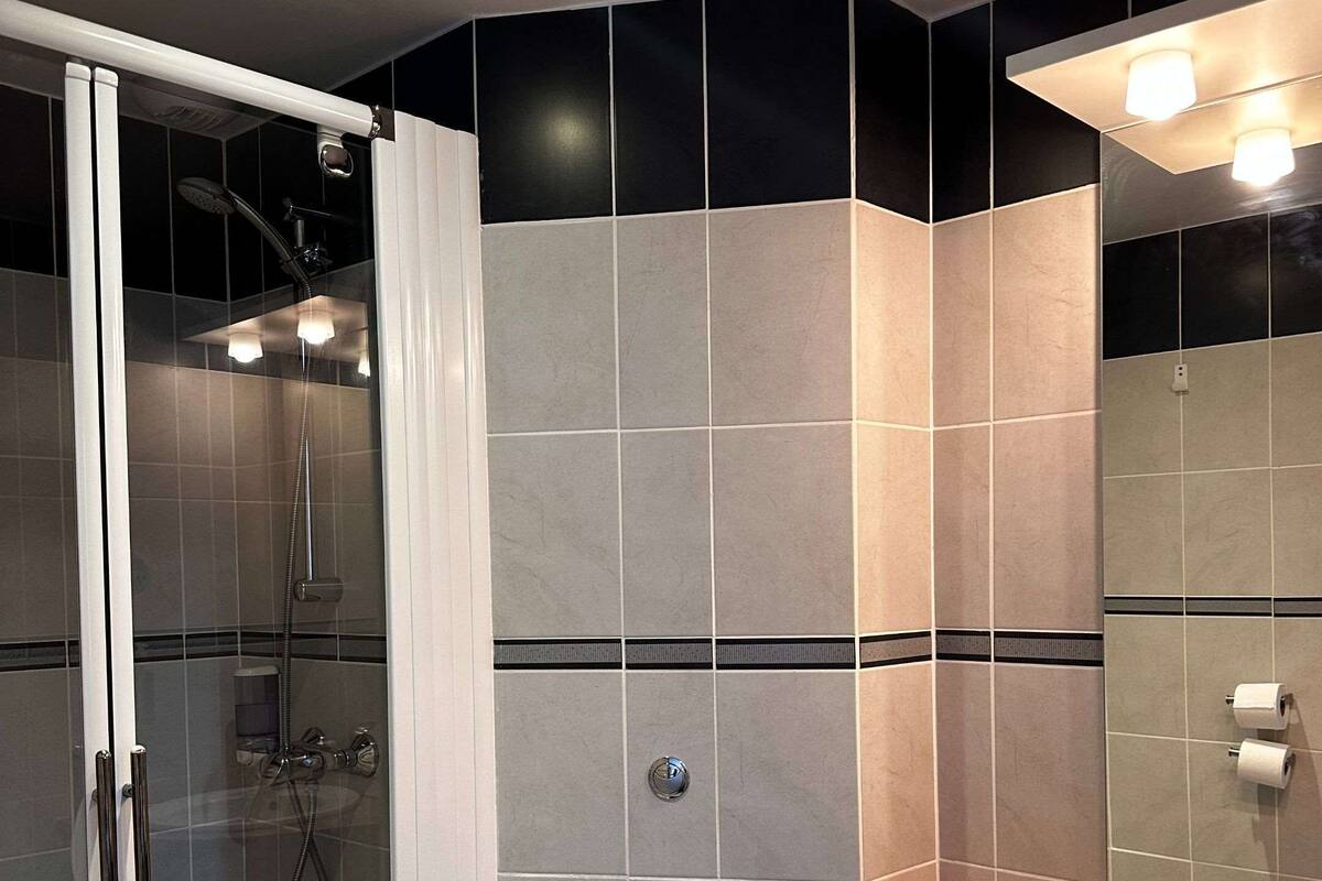 Une salle de bain moderne avec une douche à parois de verre, des toilettes blanches et un meuble-lavabo en bois avec un miroir.