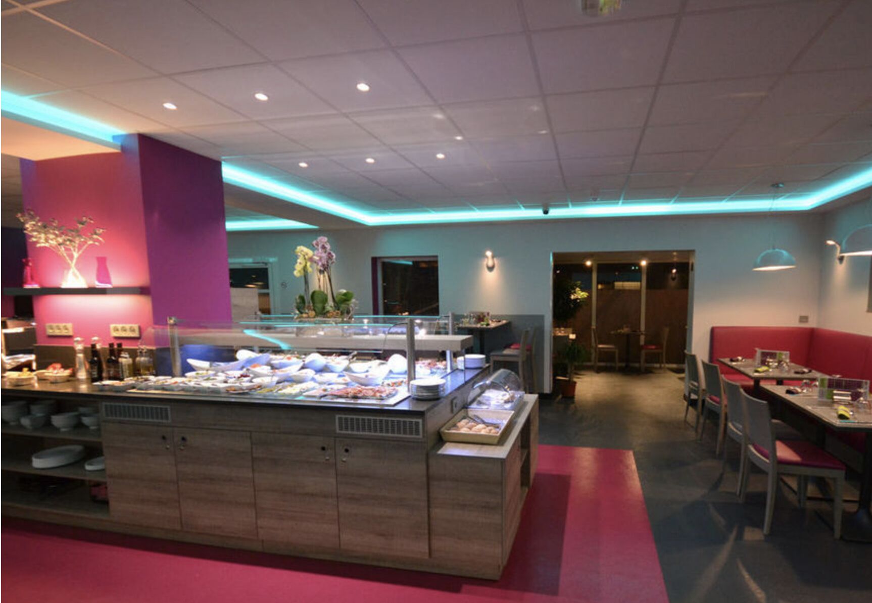 A buffet area with a variety of food items, a seating area with tables and chairs, and a decorative plant arrangement.