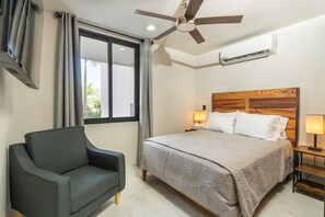 A bedroom with a bed, a chair, a ceiling fan, and an air conditioning unit.