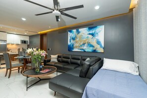 A modern living room with a sofa, coffee table, and a painting on the wall.