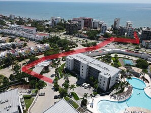 A hotel with multiple floors, a swimming pool, and a view of the ocean.