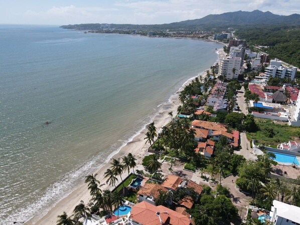 A coastal area with a beach, residential buildings, and a clear view of the sea.