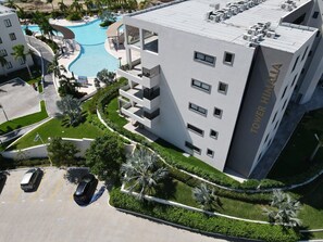 A modern hotel with a swimming pool, parking area, and well-maintained landscaping.
