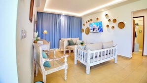 Een woonkamer met een bank, een fauteuil, een salontafel en een televisie.