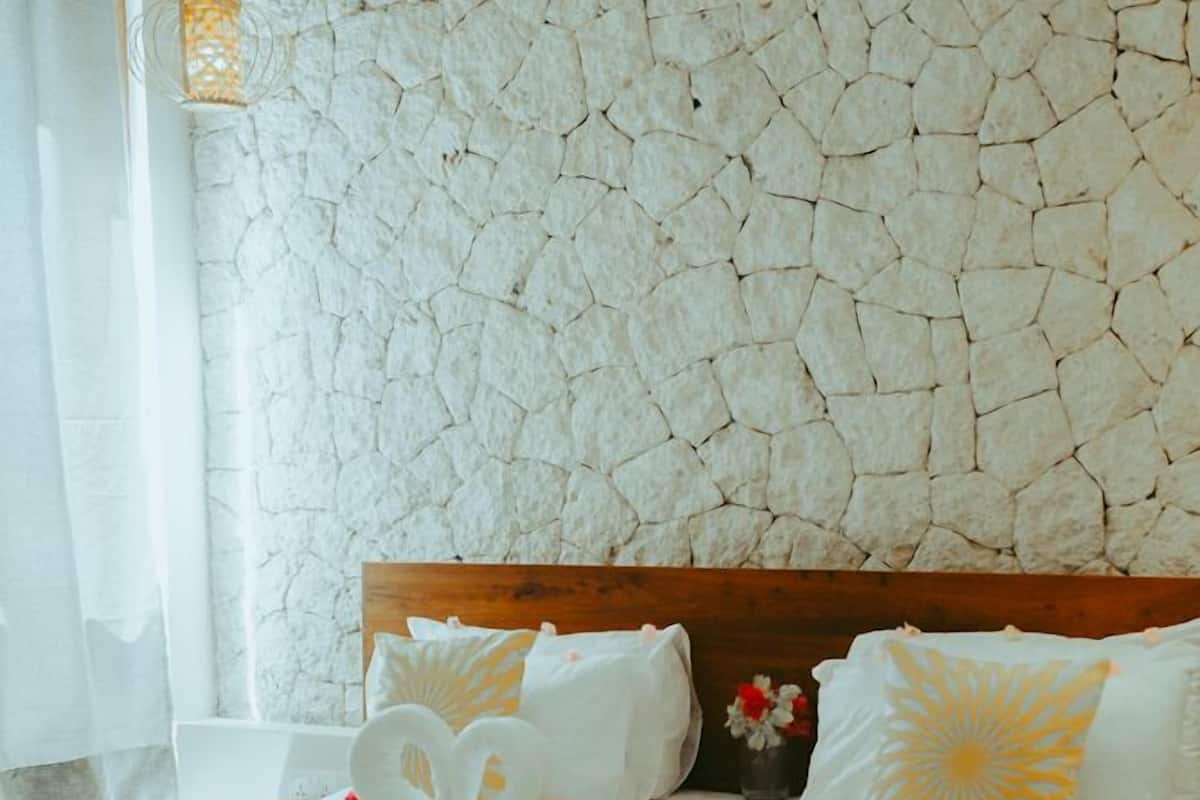 Un lit bien fait, avec un drap blanc, une tête de lit en bois et un coussin décoratif.