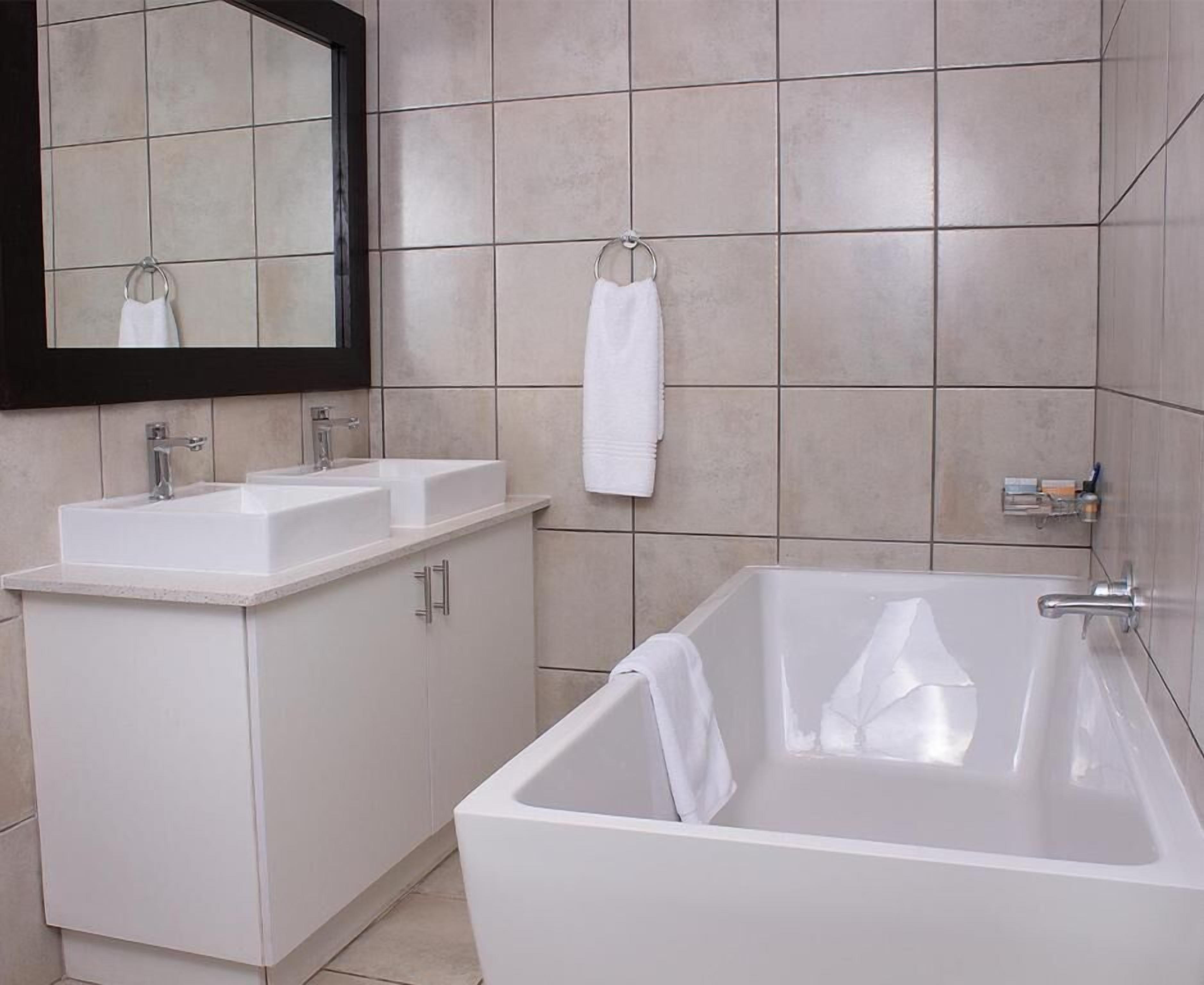 Un baño con un lavamanos blanco, un espejo y una bañera.