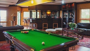 A pool table with balls, a bar area with stools, a bookshelf, and a seating area with a sofa and chairs. - Cussonia Country Home (Tierpoort)