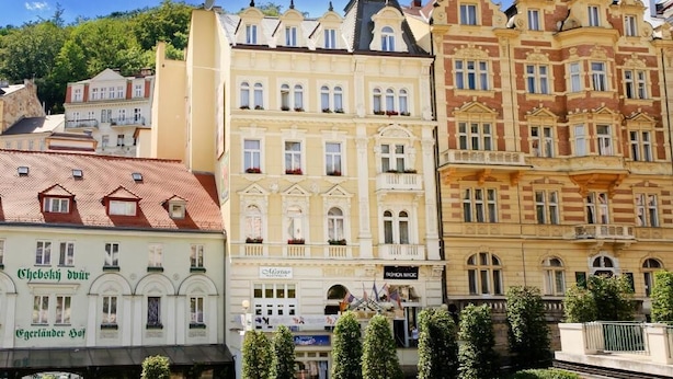A row of historic buildings with varied architectural styles, including a building with a sign that reads 'Fashion Magic.' - Hotel Heluan (Karlovy Vary)