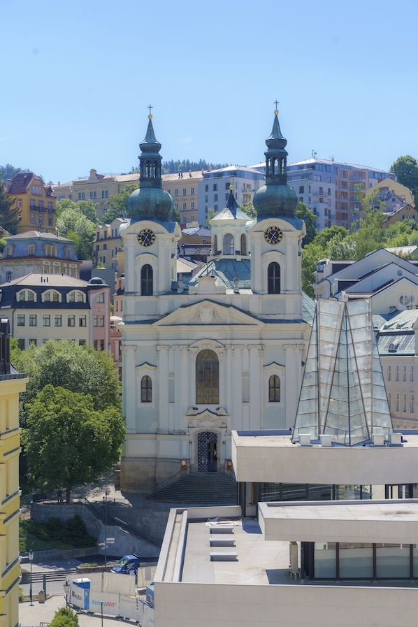 A historic church with two towers and a clock, surrounded by modern buildings.