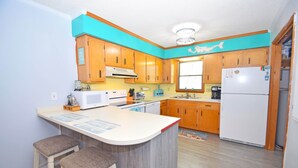 A kitchen with wooden cabinets, a white refrigerator, a microwave, and a sink. - Nanticoke Square 207B-Bayside 142nd St, Pool, W/D, AC, Free WIFI (Ocean City)