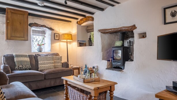 Una sala de estar acogedora con un sofá, una mesa de madera, un televisor y una chimenea.