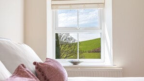 A bedroom with a large window, a radiator, and a bed with pillows. - Mill Cottage - sleeps 2, dog friendly, peaceful with parking (Windermere)