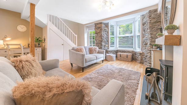 A spacious living room with a fireplace, a staircase, and large windows. - Pottery Gate - sleeps 4 in modern dog friendly cottage with parking and new bathroom (Bowness-on-Windermere)