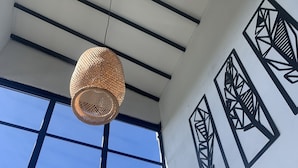 A room with a large window, geometric wall art, and a woven pendant light. - Beautiful villa overlooking the forest + jacuzzi (Guarne)