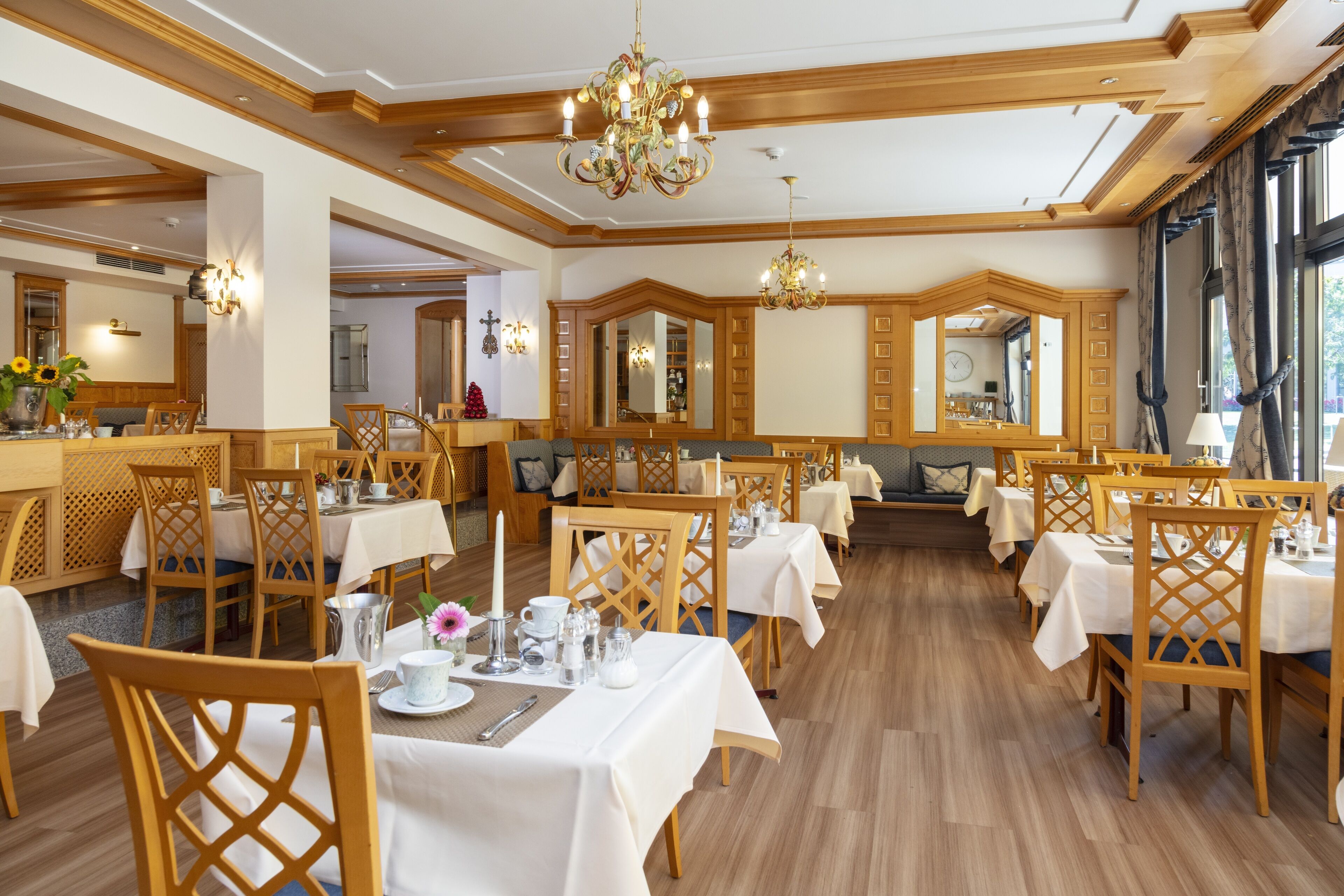 Un comedor con sillas y mesas de madera, candelabros y un espejo grande.