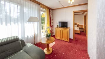 Habitación de hotel con sofá, una mesita redonda con lámpara, televisor y mueble de madera.