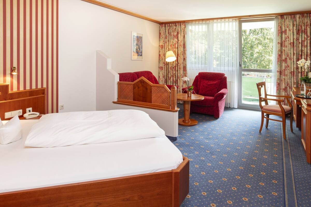 Une chambre d’hôtel avec un lit, un bureau doté d’une lampe, une chaise et une vue sur l’extérieur par une fenêtre.