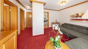 Une chambre d’hôtel avec une moquette rouge, un canapé, une armoire en bois et un tableau accroché au mur.