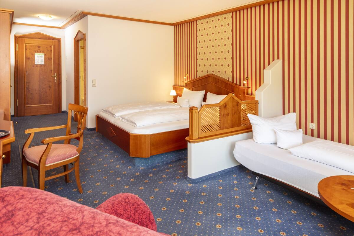 Une chambre d’hôtel avec un lit, un canapé, une chaise et une petite table.