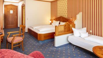 Une chambre d’hôtel avec un lit, un canapé, une chaise et une petite table.