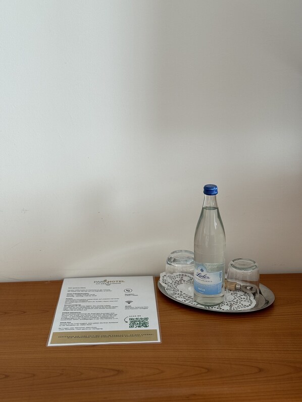 A hotel room with a wooden table, a bottle of water, and a menu on the table.