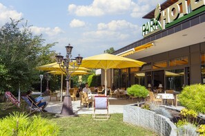 Un espace extérieur aménagé en terrasse, avec des parasols jaunes, des tables et des chaises.