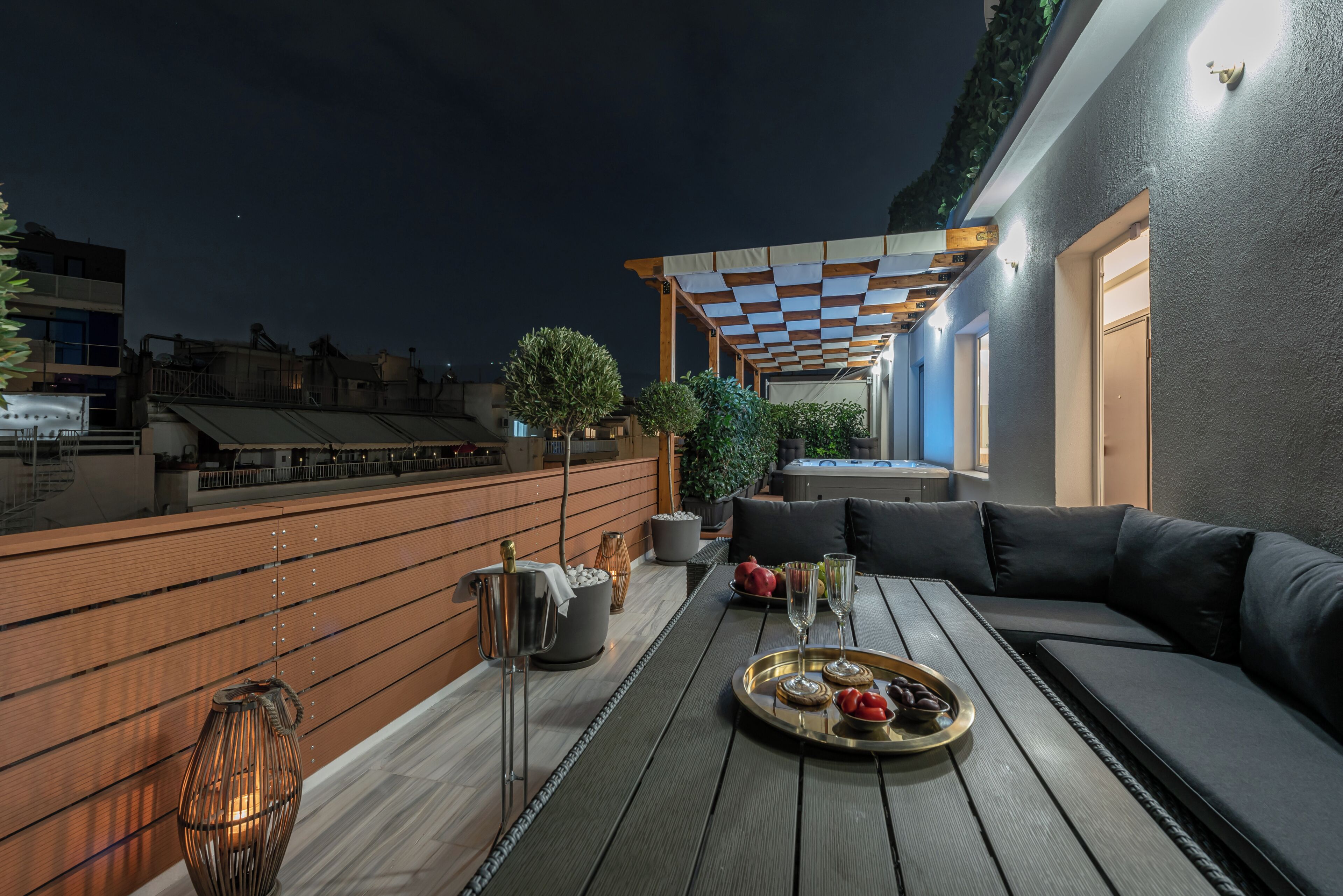 En takterrass med ett trädäck, en soffa, ett bord med ett fat med mat och en bubbelpool.