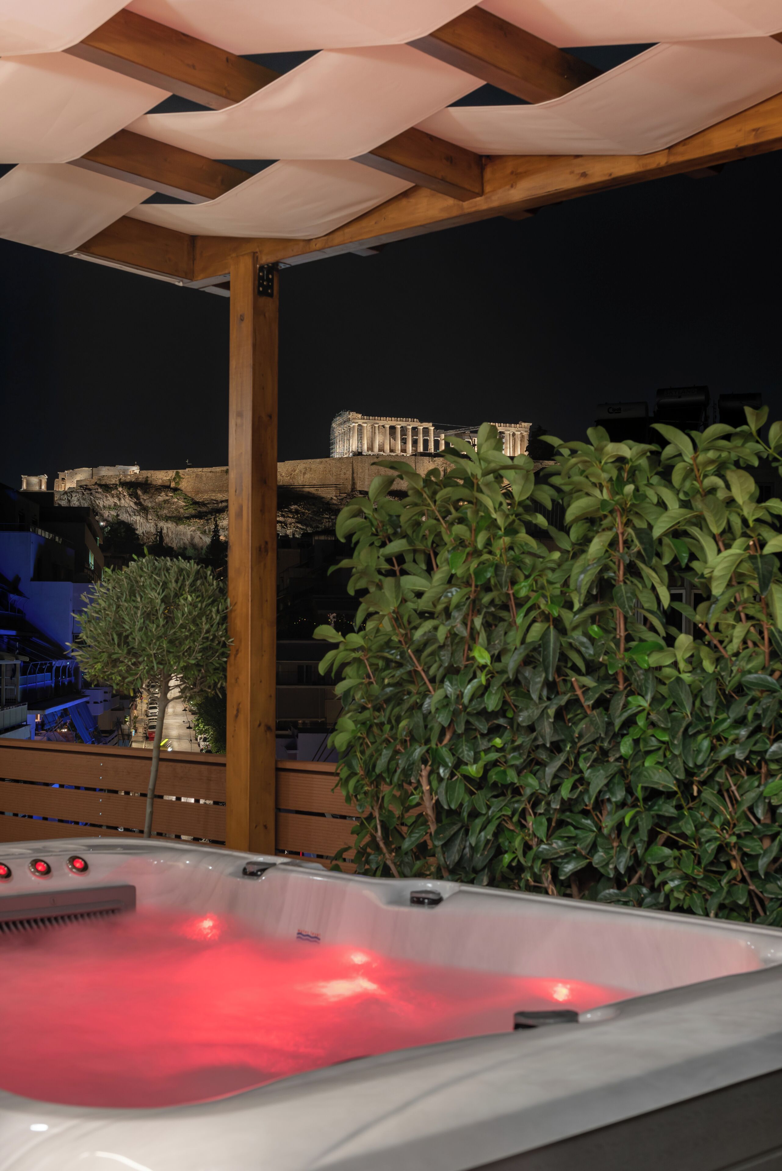 A hot tub under a wooden pergola with a view of a historic building in the background.