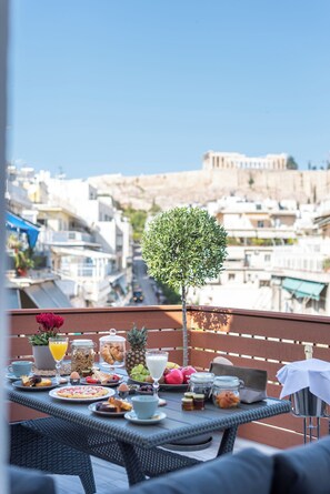 Un balcón con una mesa dispuesta para el desayuno, con vistas a la ciudad.