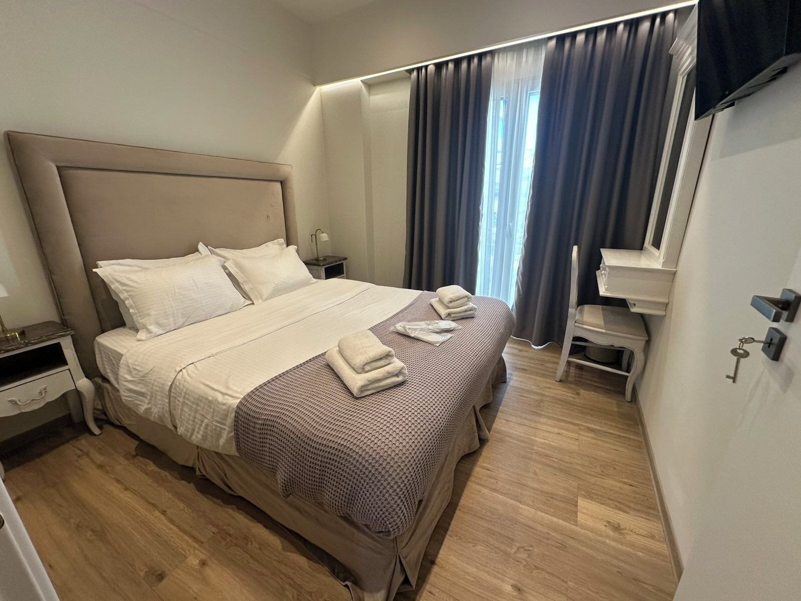 A hotel room with a large bed, a nightstand, a desk, and a chair.