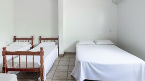 A room with two wooden beds, white bedding, and a white air conditioning unit on the wall. - Pousada Caldas Novas (Caldas Novas)